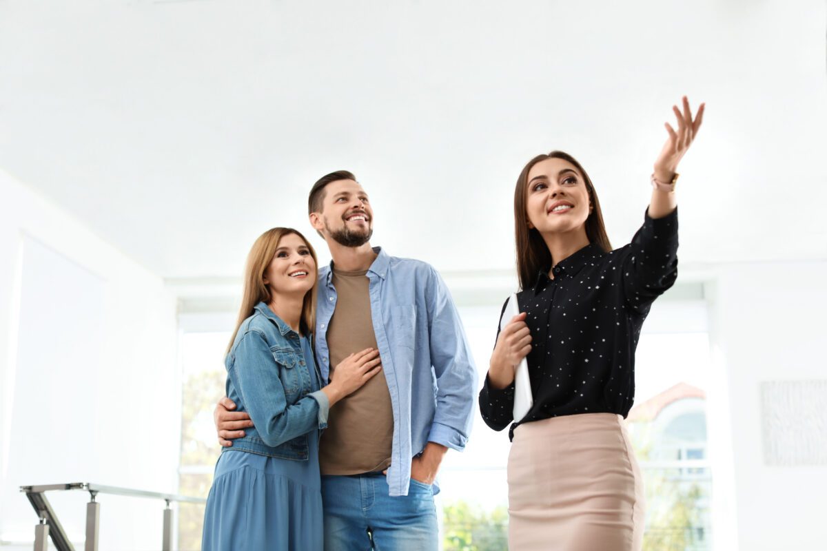 Female real estate agent showing new house to couple, indoors
