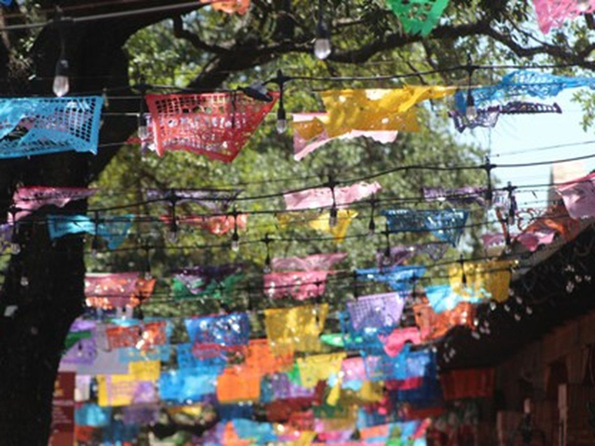 Colorful papel picado banners and string lights hanging outdoors during Fiesta season in San Antonio, Texas