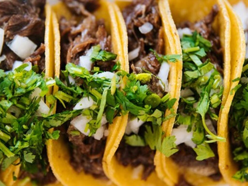 Street-style tacos with shredded beef, fresh cilantro, and diced onions, a popular food during Fiesta season in San Antonio, Texas