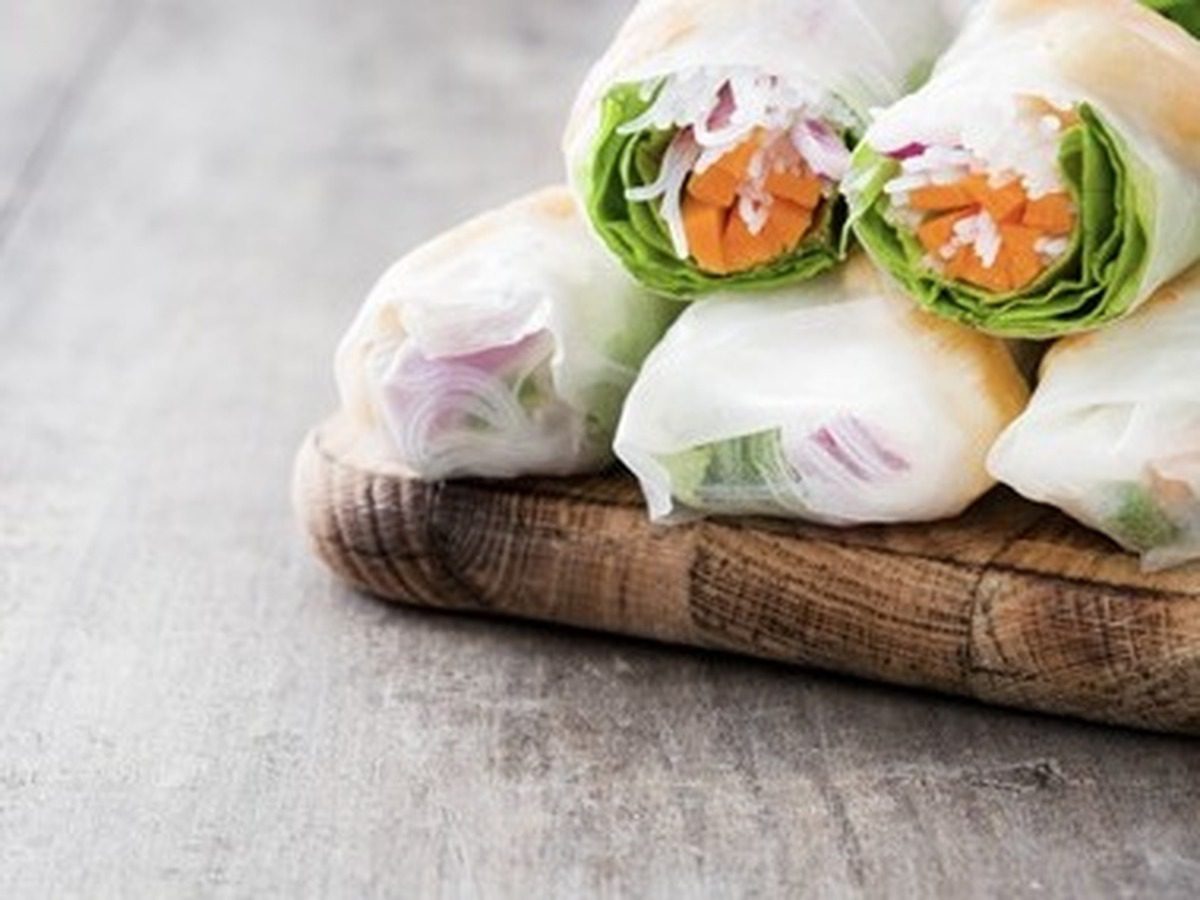 Spring rolls with vegetables, rice noodles and prawns on wooden background