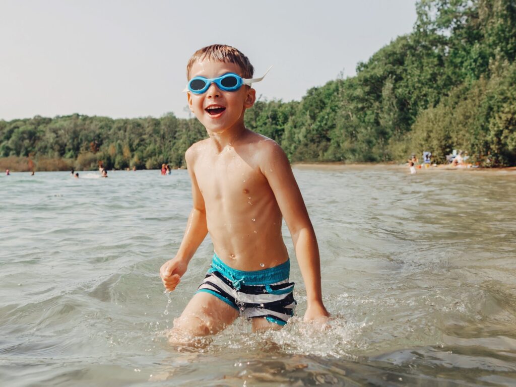 Boy playing and swimming in a river wearing underwater goggles.