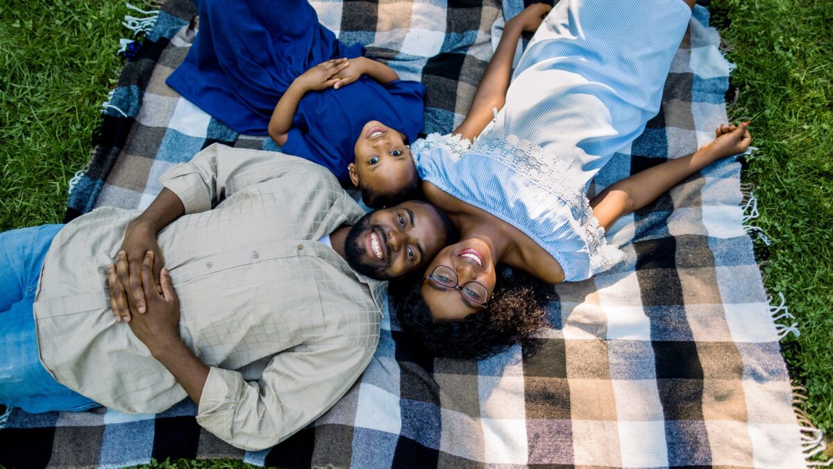 Happy young family laying on a picnic blanket together