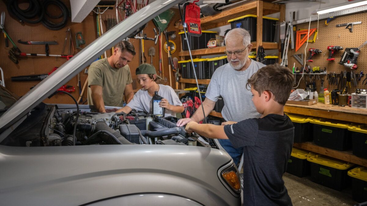 Three generations working on a car in the garage