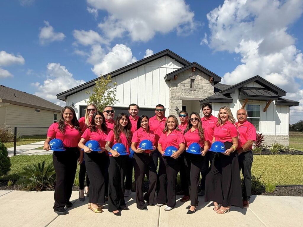 Team photo of Hakes Brothers team members standing in front of a new home with hard hats.