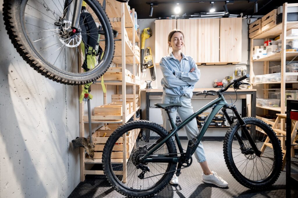 Young woman standing with a bicycle in an organized garage at home.