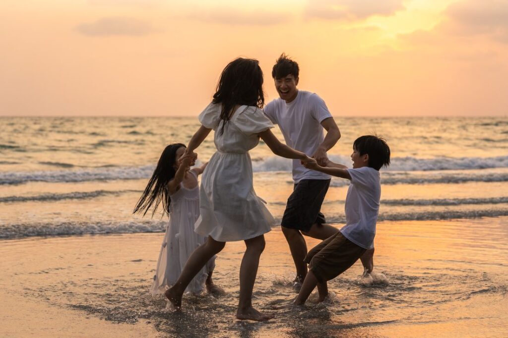 Happy family playing on the shore at sunset