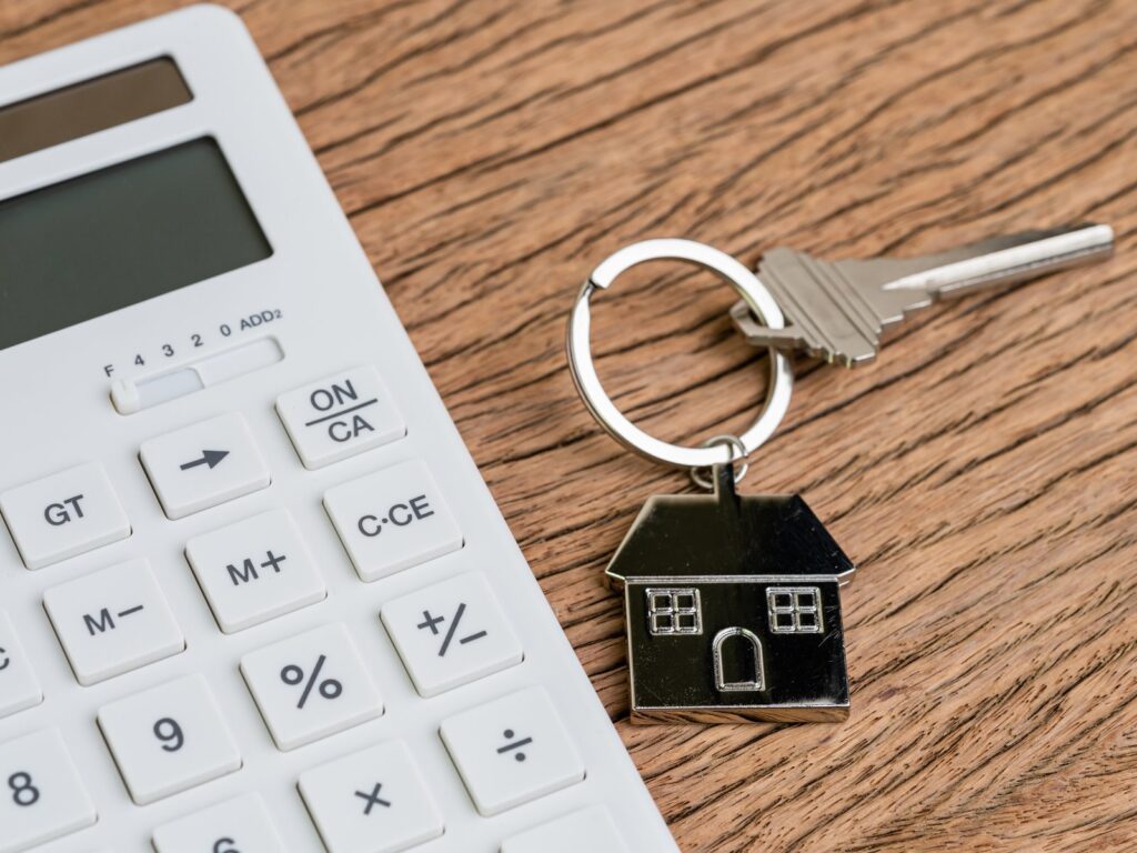 Home key with house keychain with white calculator for mortgage calculation