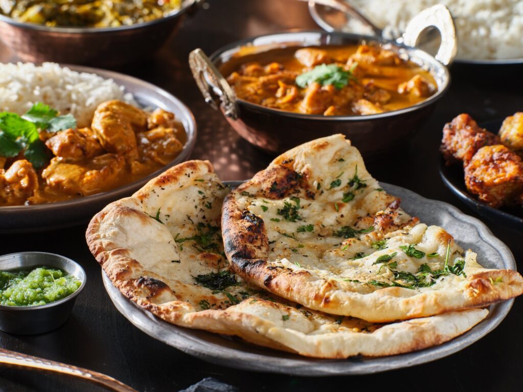 Indian naan bread with a variety of Indian dishes around it.