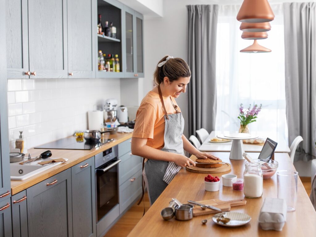 Happy, smiling young woman making cake on kitchen at home