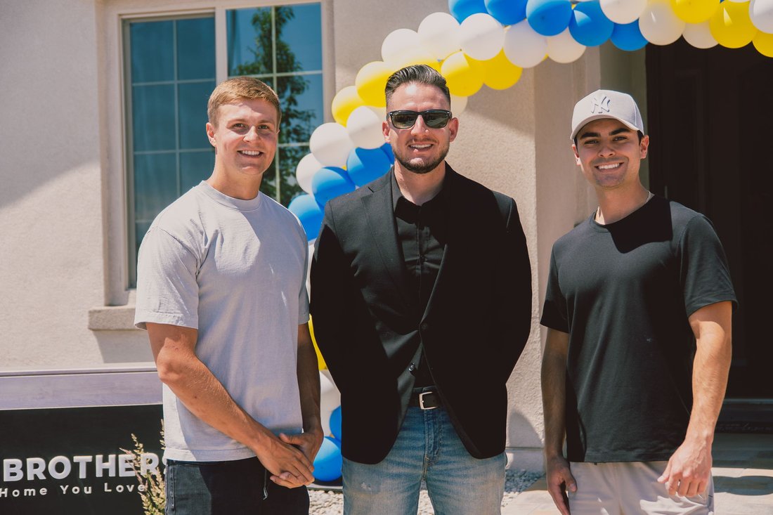 Three Hakes Brothers employees standing in front of a home adorned with balloons.