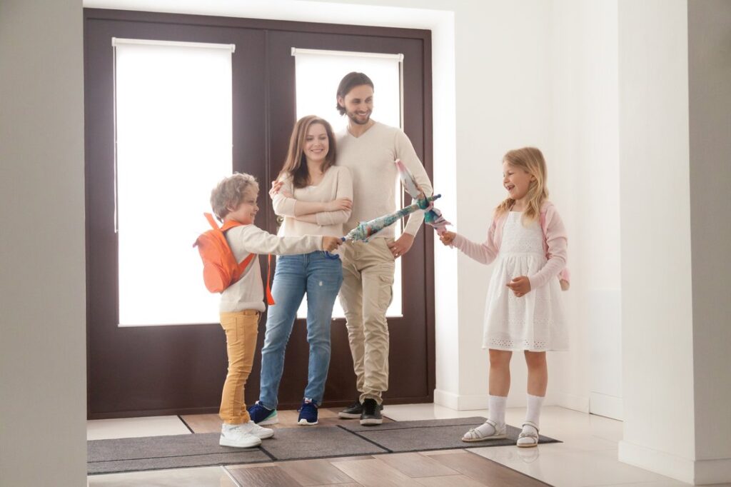 Family staying in home’s front hallway with umbrellas.