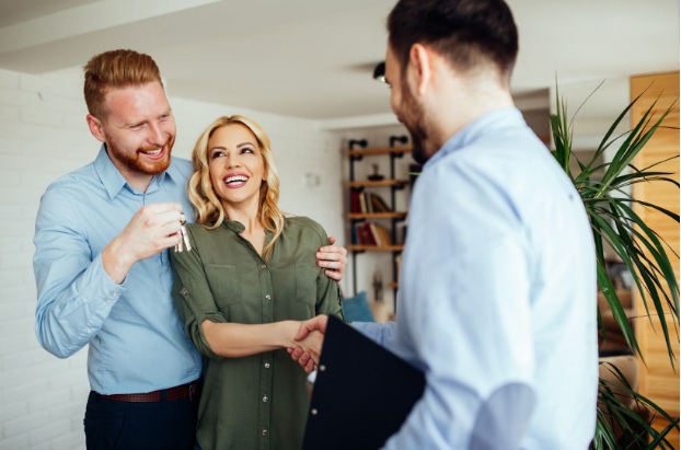 Happy couple accepting keys from a real estate agent at home