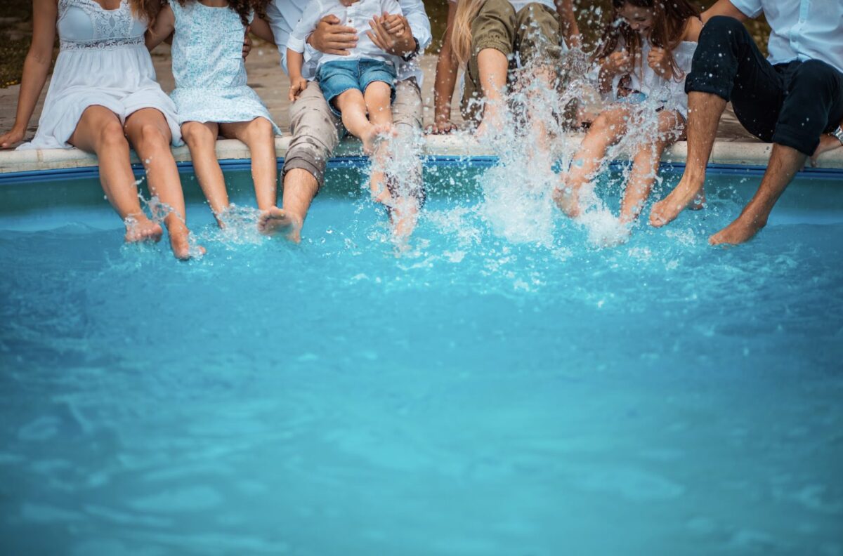 Family sitting poolside while splashing their feet in the water