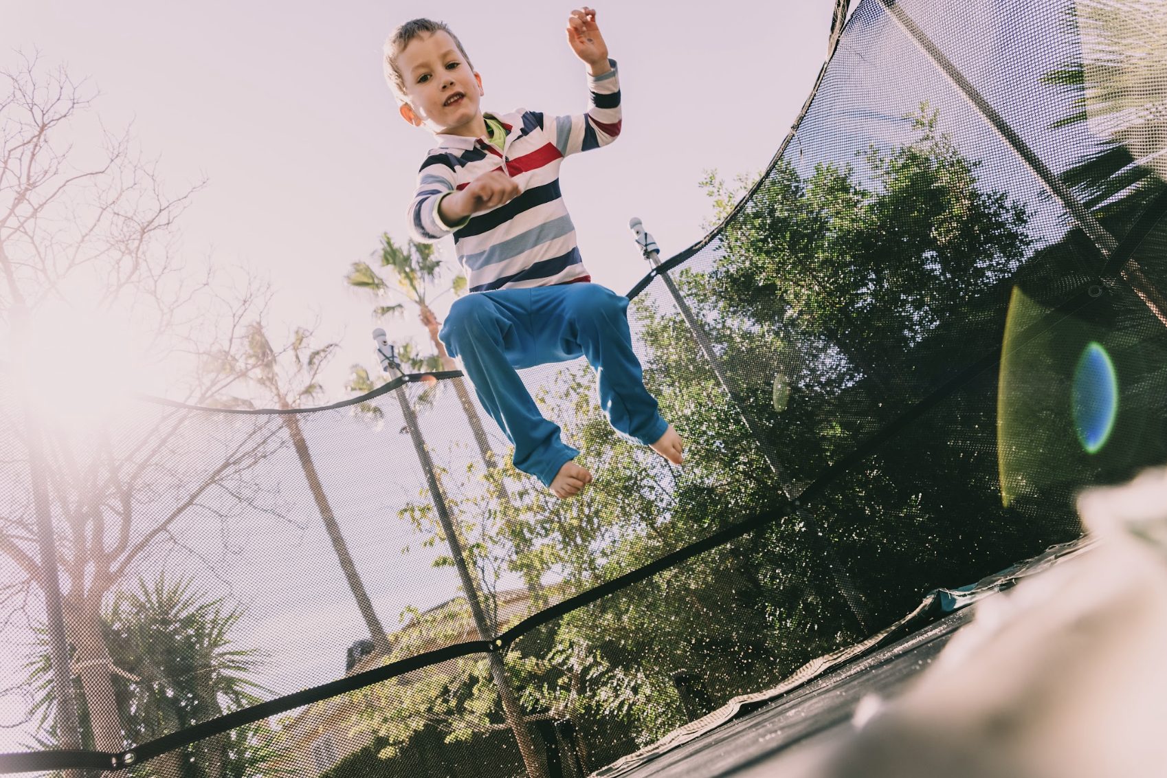 Young boy jumping on a trampoline in the backyard