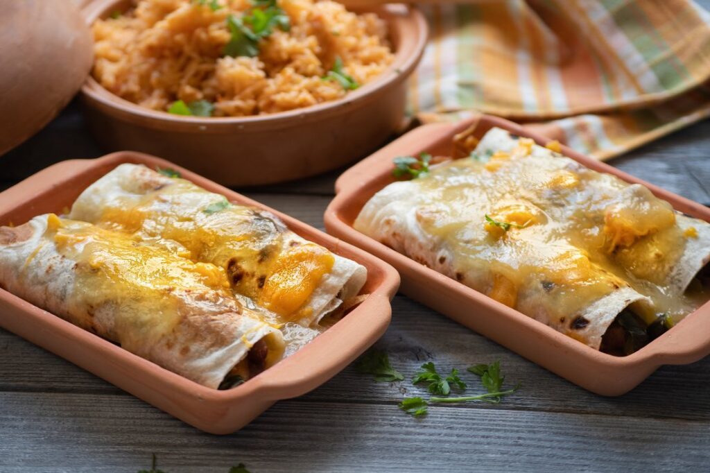 Enchiladas with green chile sauce served in clay dishes.