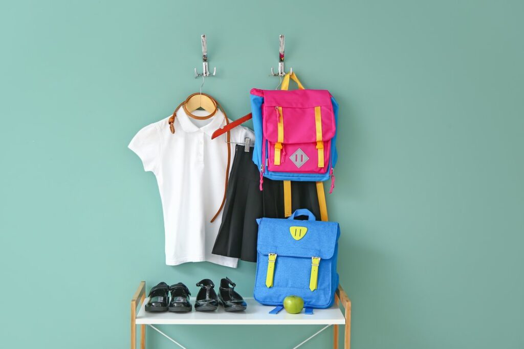 Stylish school uniform with backpacks near color wall
