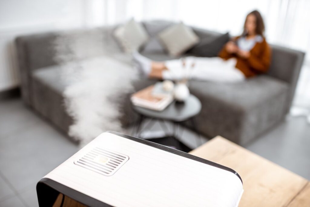 Woman relaxing on the couch at home with a humidifier in the foreground.