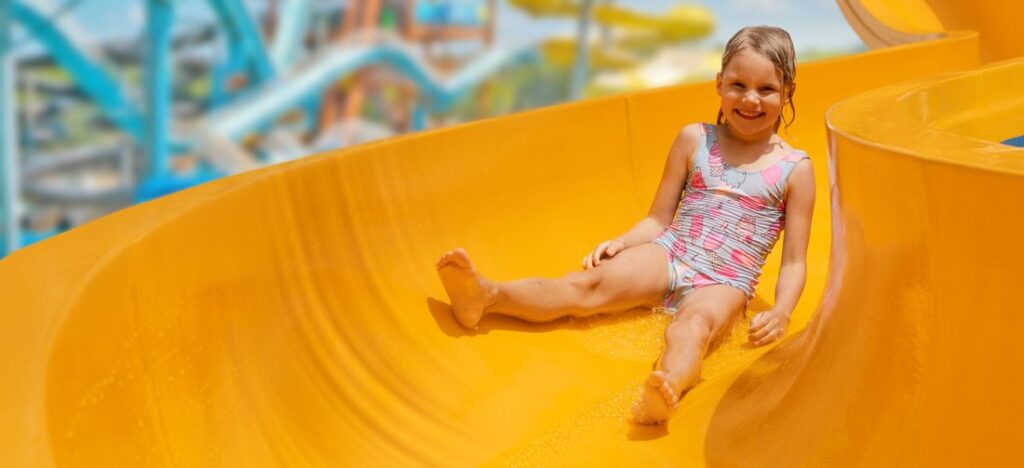 Happy child on slide at outdoor water park