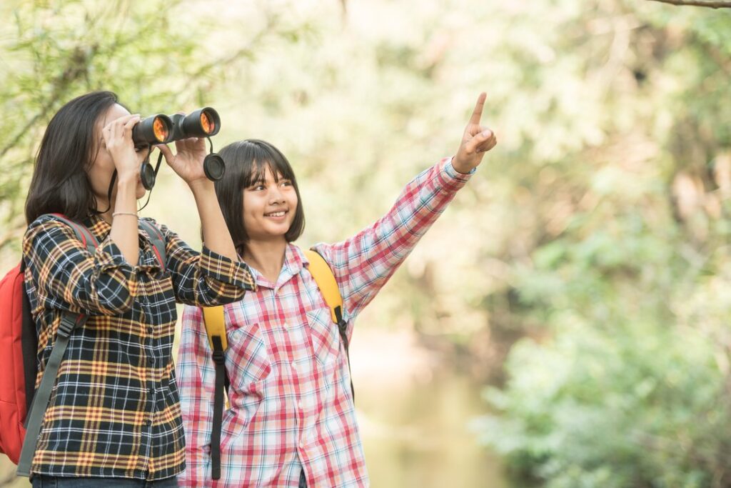 Mother and daughter birdwatching in nature.