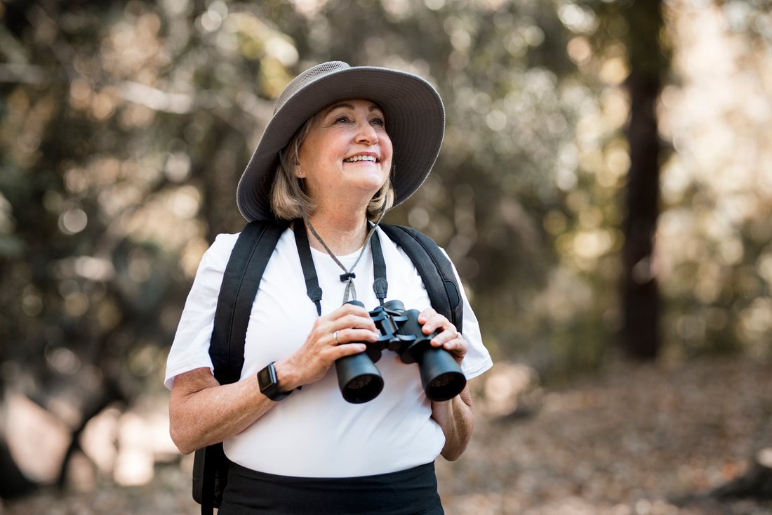 Active woman using binoculars to see the beauty of nature